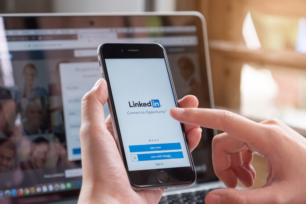 A person holding a smartphone showing the LinkedIn sign-in screen.
