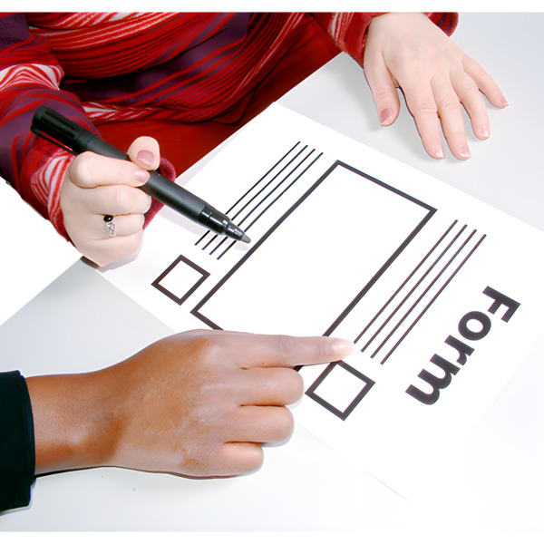 One hand holding a pen to complete a form while another person points to the form to provide guidance.