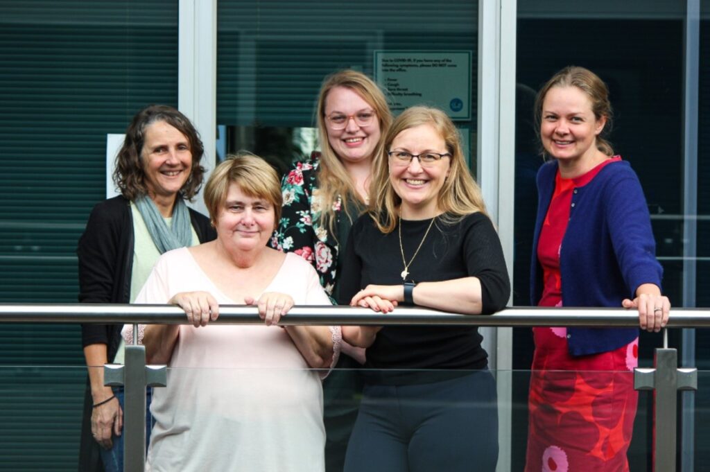 5 women standing next to each other smiling