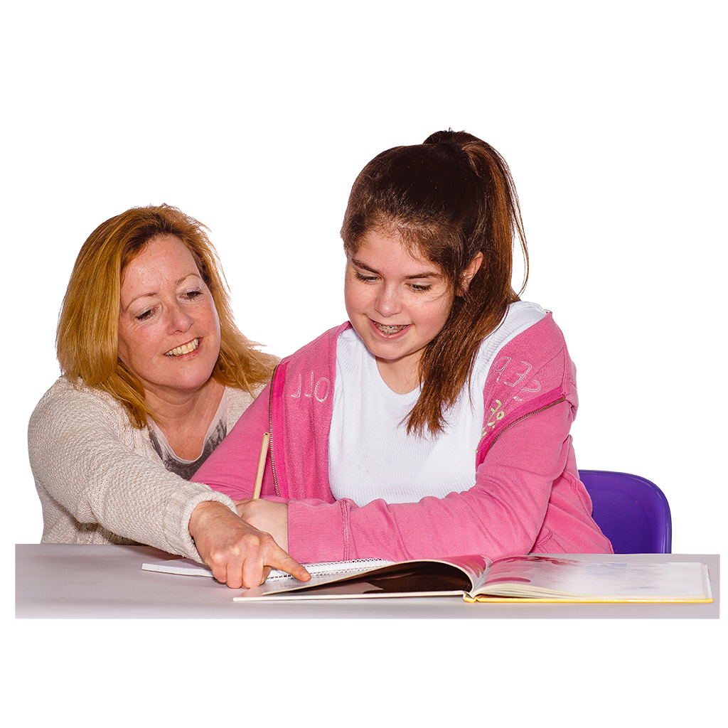 A woman pointing at a book while helping a young girl study at a desk.