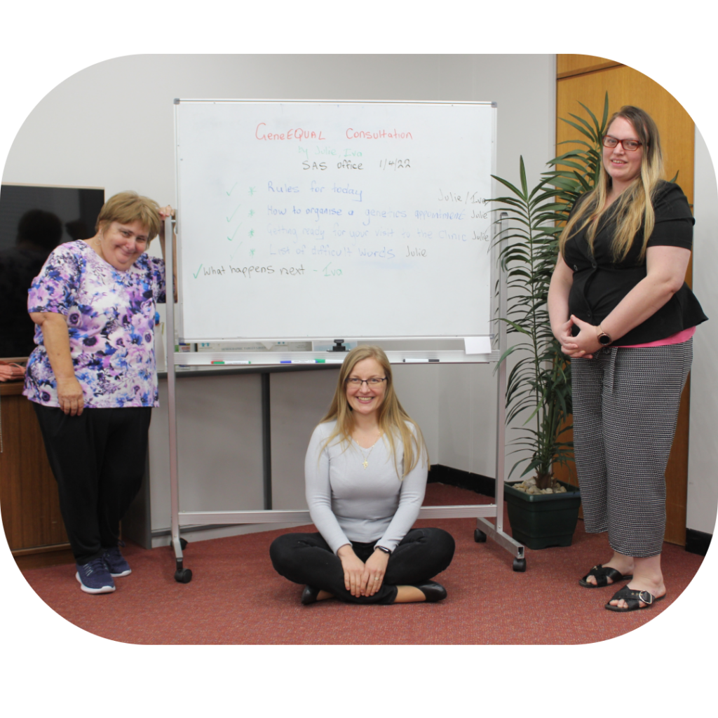 Three smiling women in front of a whiteboard covered with written ideas.