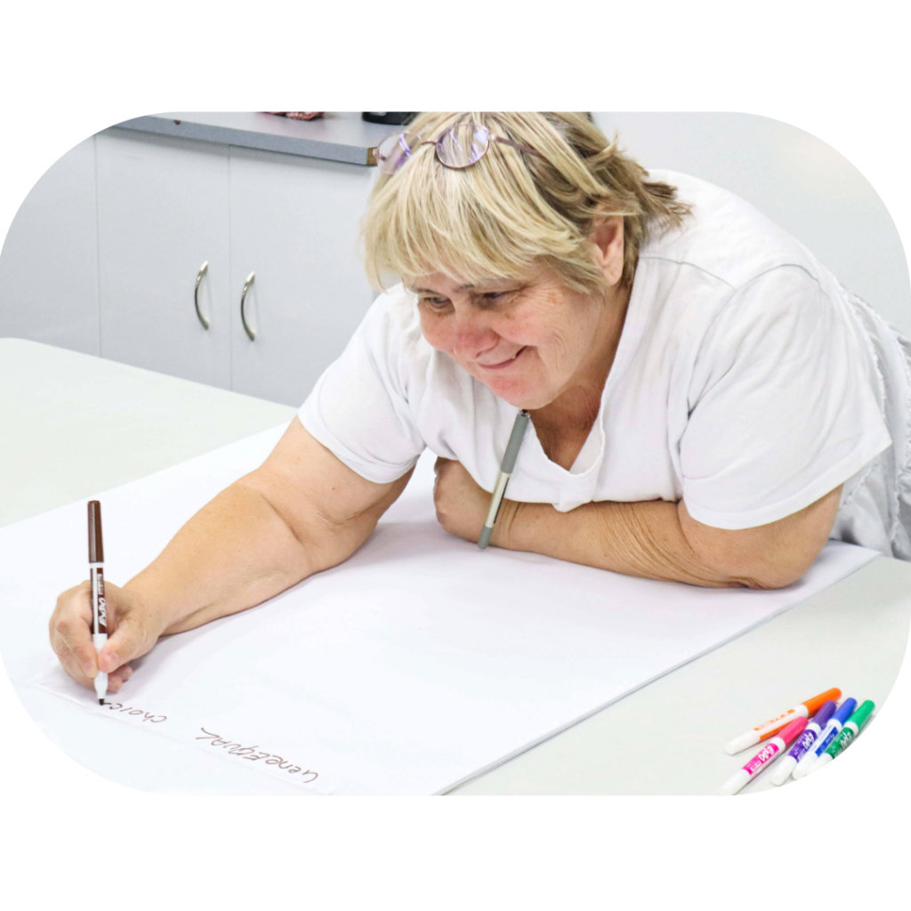 A woman holding a pen and writing ideas on a large sheet of paper.