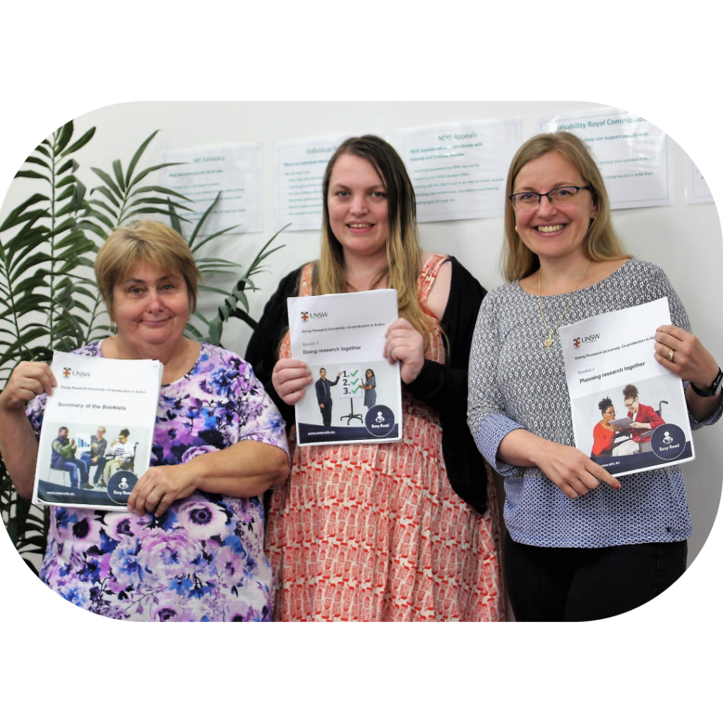 Three women holding booklets and smiling.